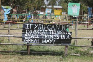 A sign outside of Fade's school grounds that says "if you can not do great things, do small things in a great way!"