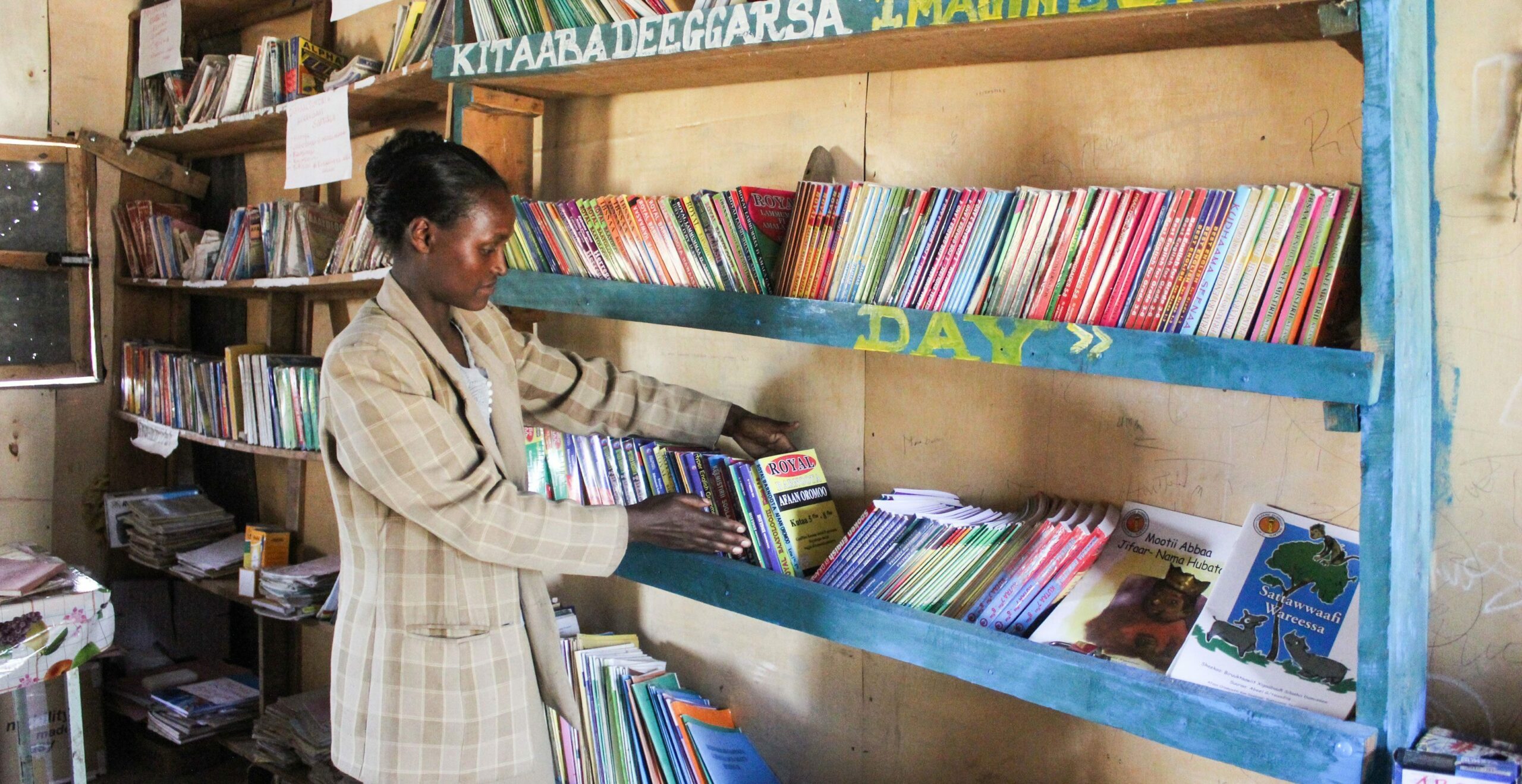 A woman organizing a shelf of books in a school library