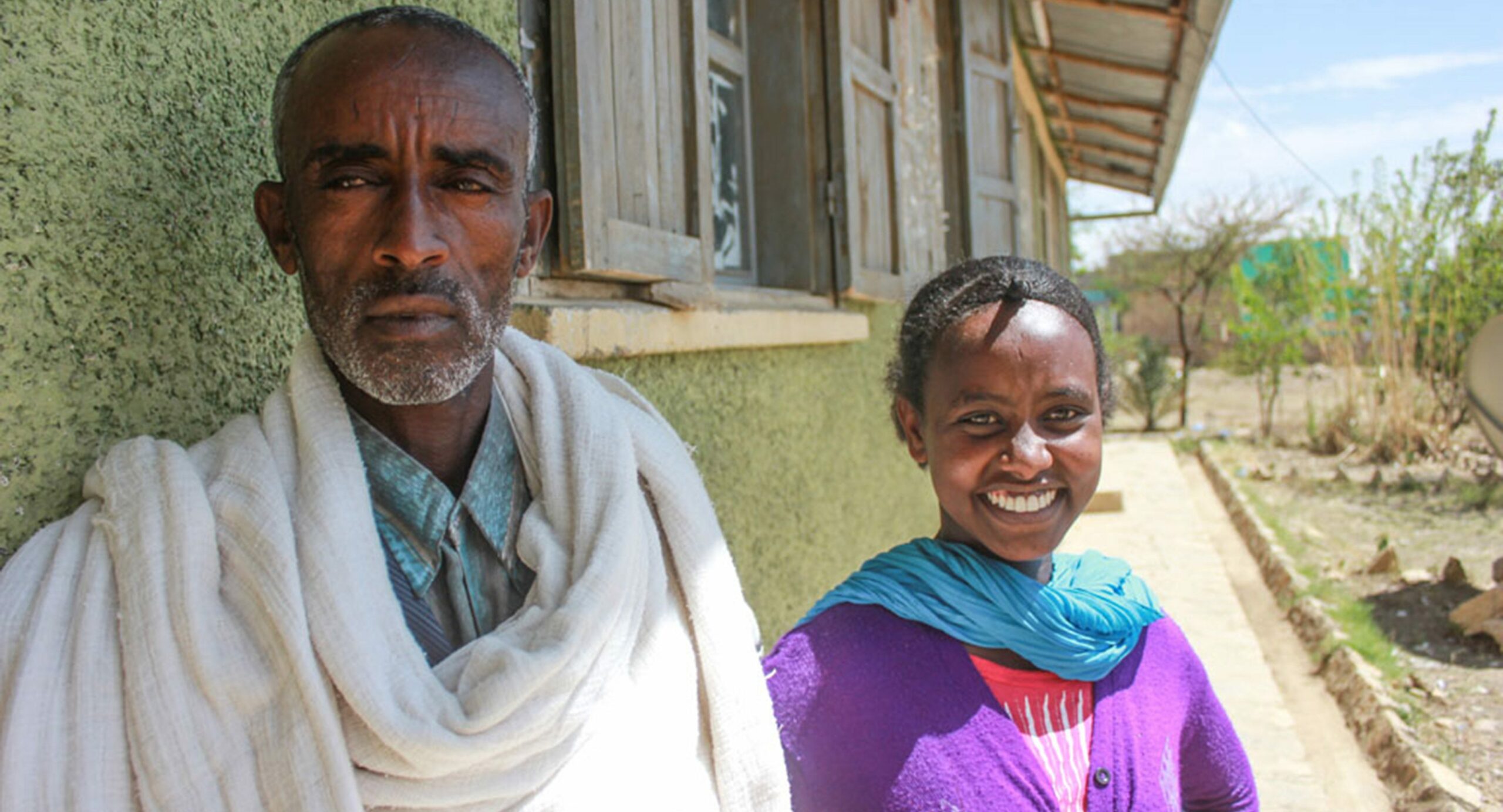 A man and a woman stand outside of a school in Ethiopia