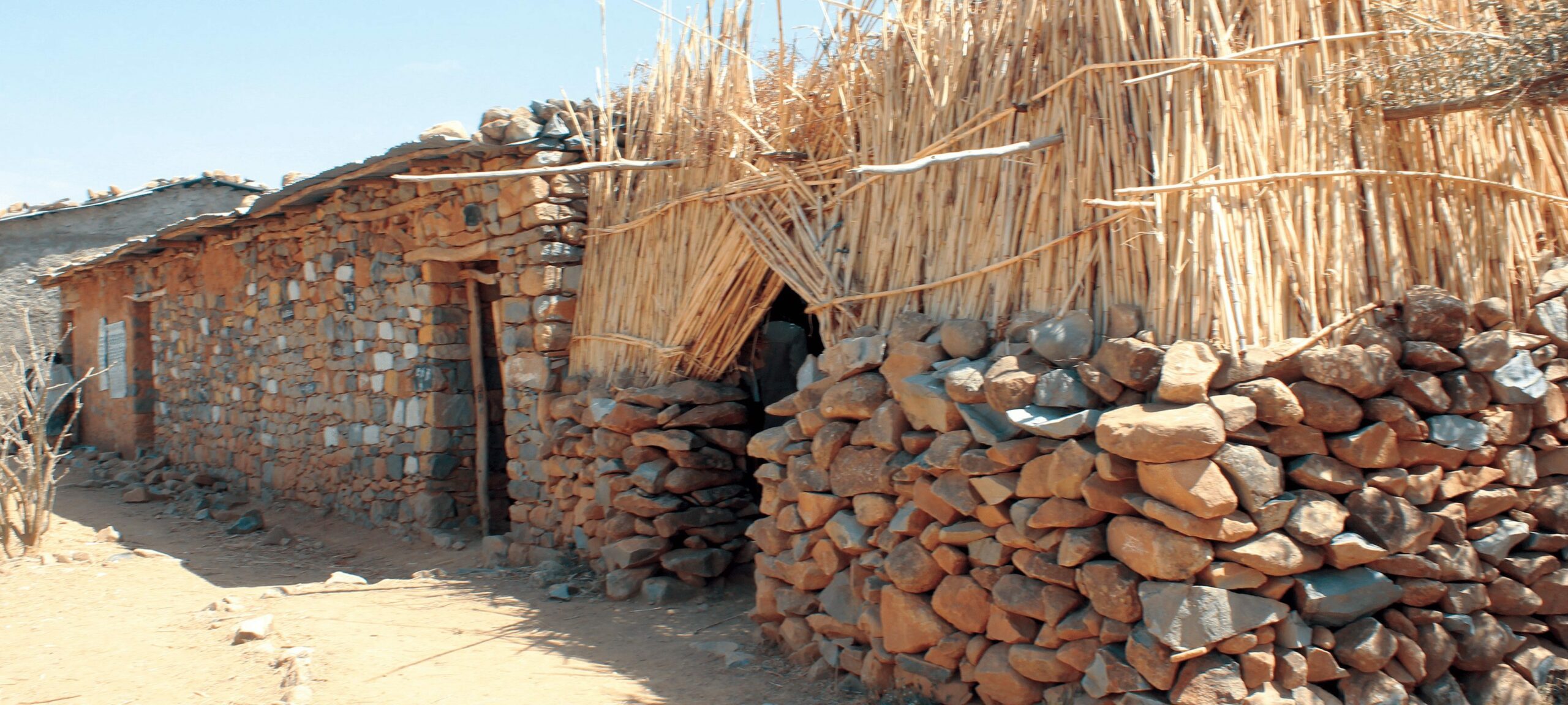 Examples of classrooms at Adisenay School, constructed of stones balanced on top of each other and sticks to create a roof.