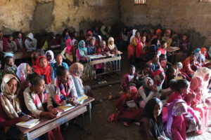 Children packed into a poor quality classroom.